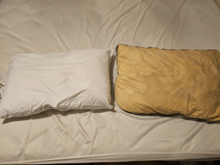 Guanciali su un letto, di cui uno pulito e candido e l'altro fortemente macchiato