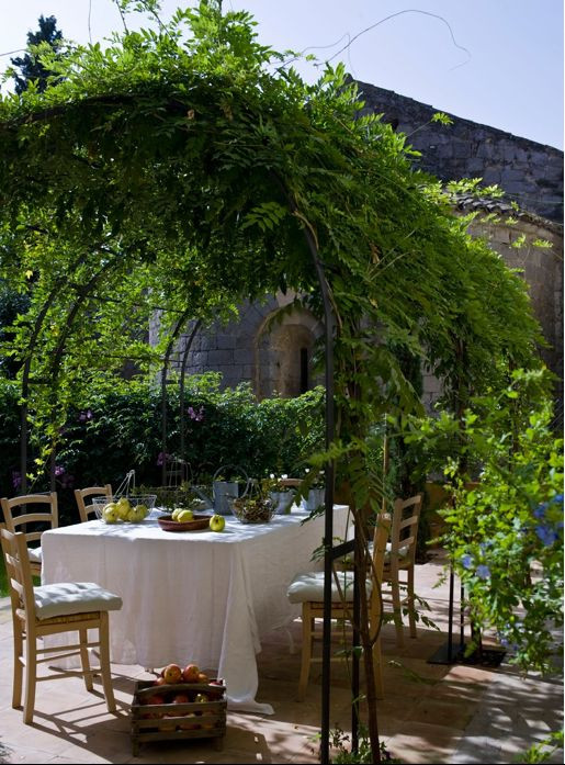 a dining area under an arched pergola, adorned with climbing plants