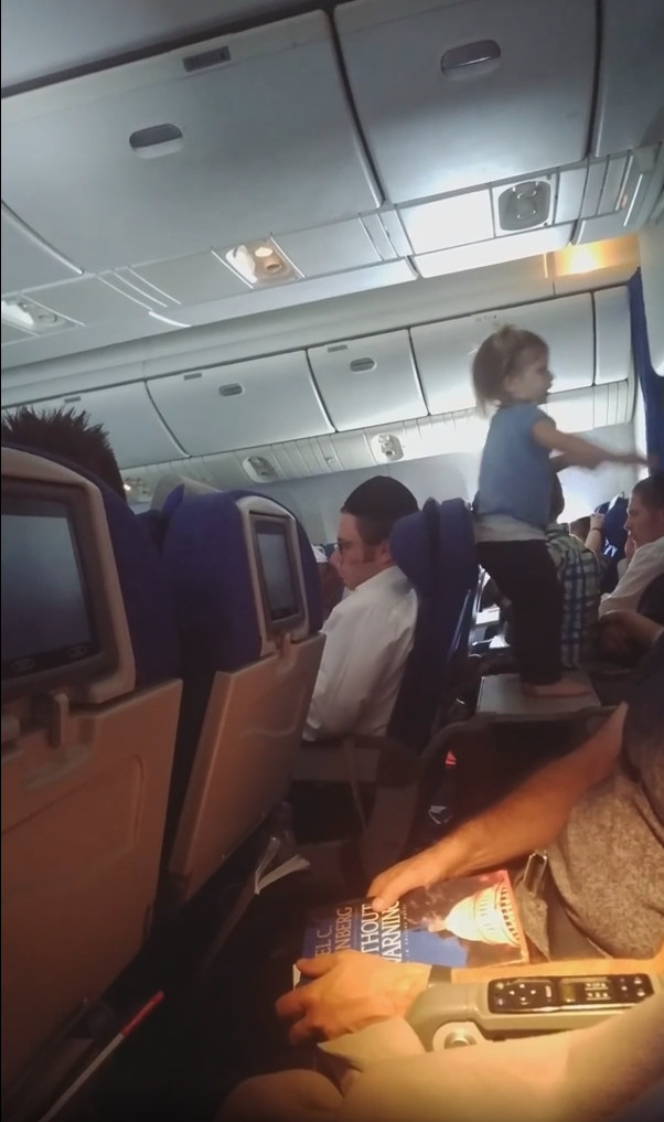 Ein kleines Mädchen springt ungebremst auf den Tisch eines Flugzeugs