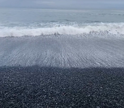 Un'onda si infrange sulla riva di Reynisfjara