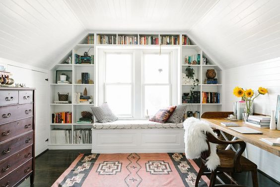Une bibliothèque et un canapé contre la fenêtre