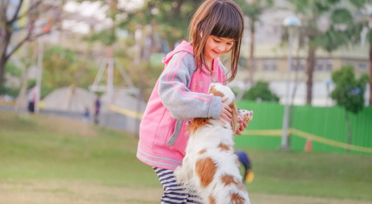 Bambina gioca con un cagnolino al parco