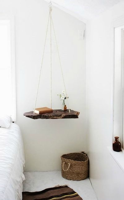 Eine grobe Holzplatte, die neben dem Bett von der Decke hängt