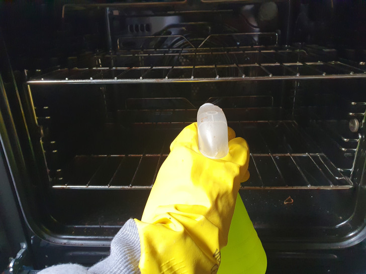 Un braccio che spruzza un prodotto all'interno di un forno da cucina
