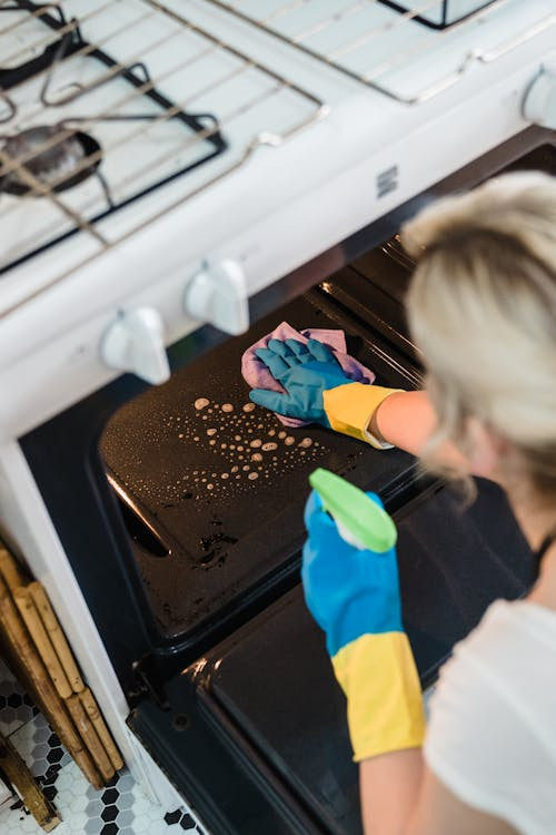 Een vrouw maakt de binnenkant van een keukenoven schoon