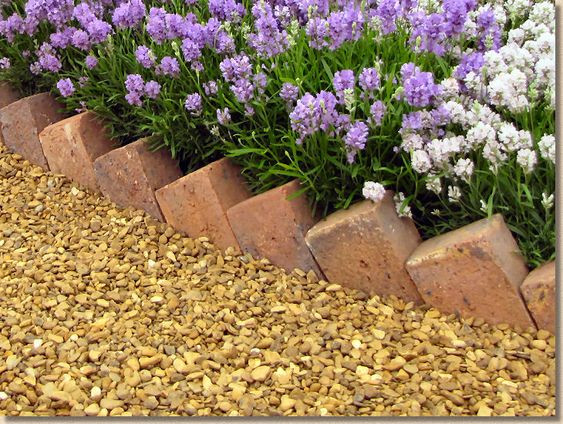 Bricks placed vertically in a herringbone pattern to border a flowerbed