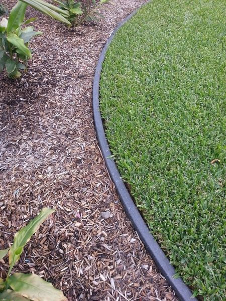 Black plastic border laid down between a flowerbed and the lawn