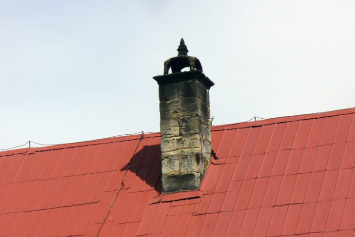 une vieille cheminée qui a noirci sur un toit