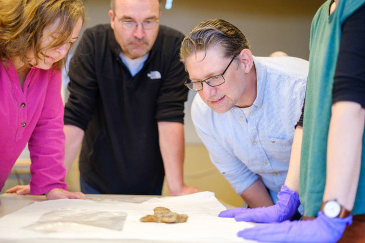 Fyra personer tittar på vikingasvärdet som hittades på en gård i Norge