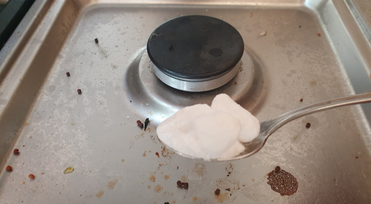 a teaspoon of sodium carbonate photographed in front of a dirty stove
