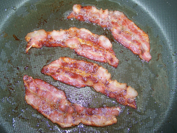 bacon being cooked in a frying pan