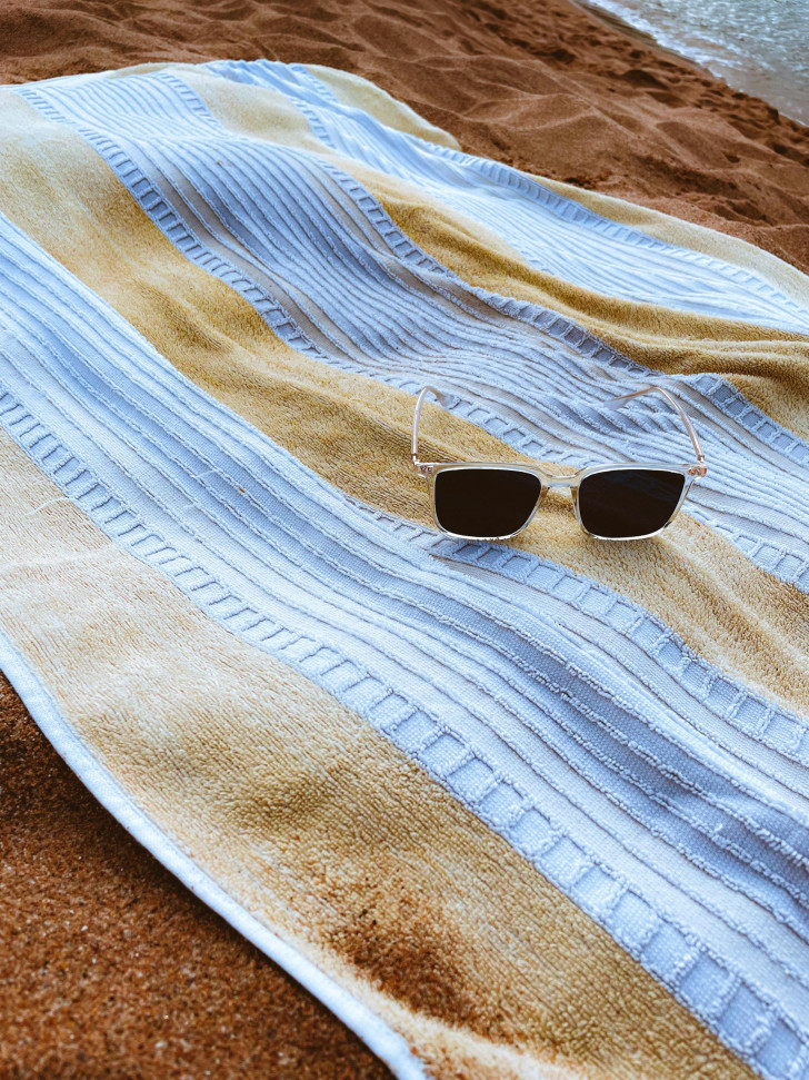 a towel spread out on the beach with sunglasses perched atop