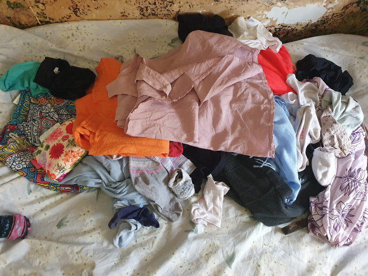 a pile of clothes and accessories placed on a bed