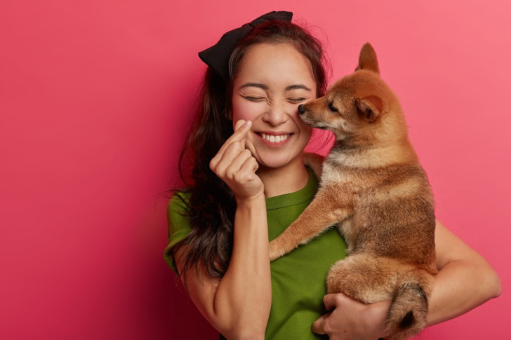 Una donna felice mentre tiene in braccio il cane che le lecca una guancia