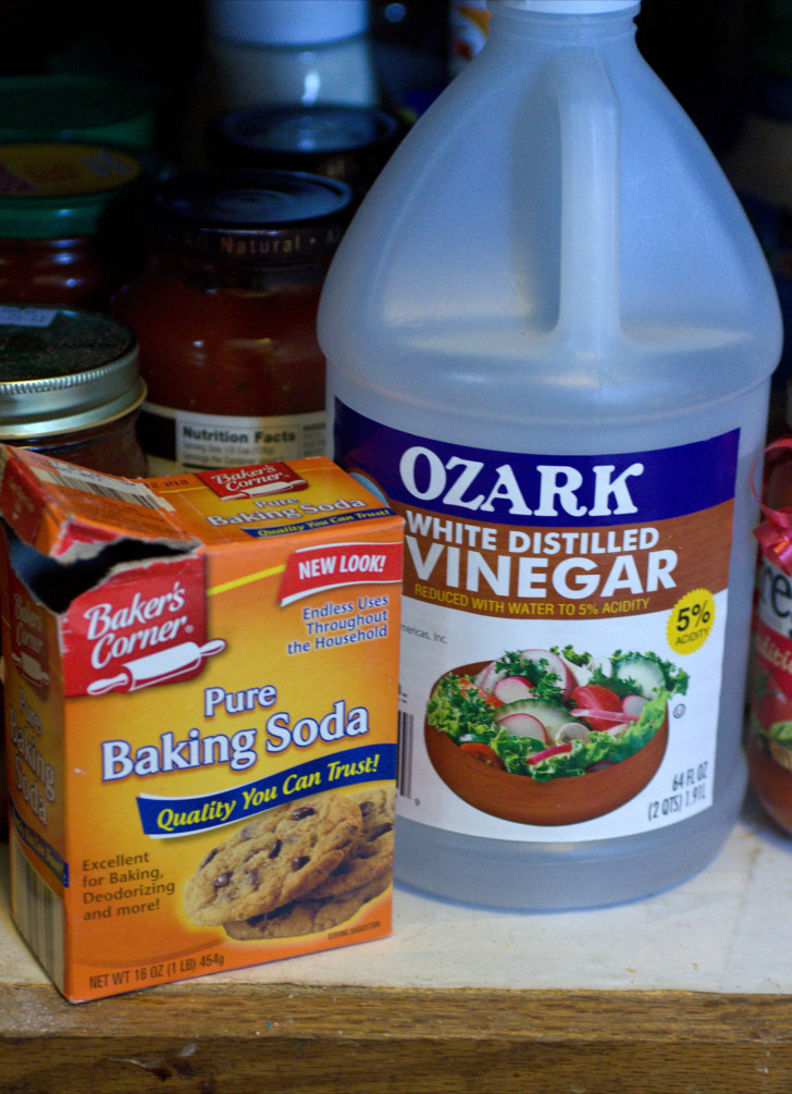 A box of baking soda alongside a jug of vinegar