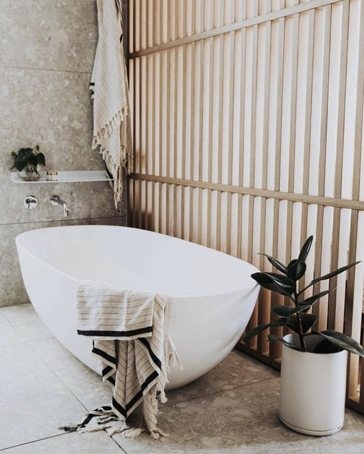 A bathroom with the floor and walls clad in rough stone with earthy tones