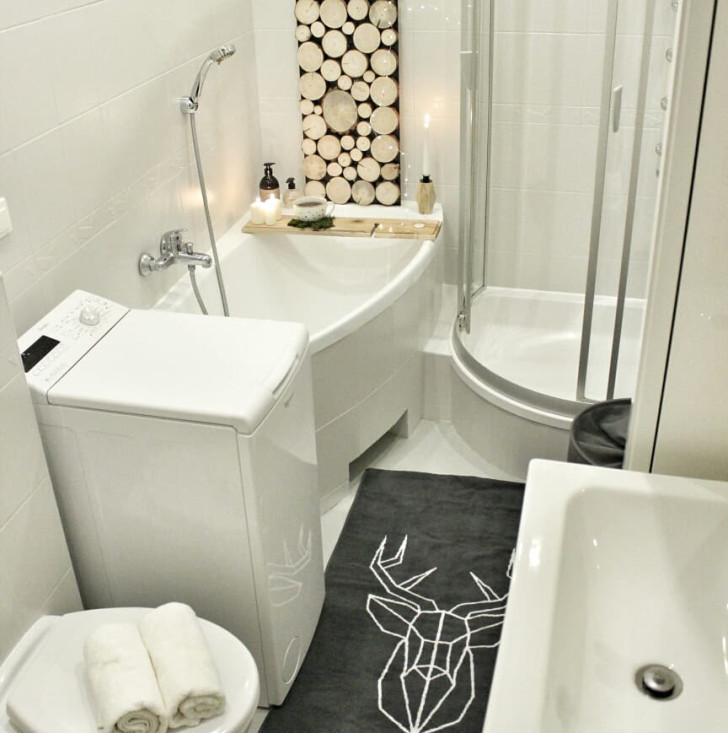 Untreated wooden discs decorate the wall above the tub in an all-white bathroom