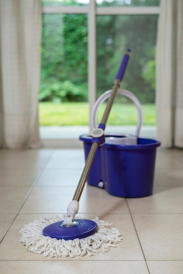 A bucket with a round mop placed on the ground