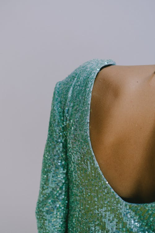 Detail of the back of a woman dressed in a low-cut dress decorated with sequins