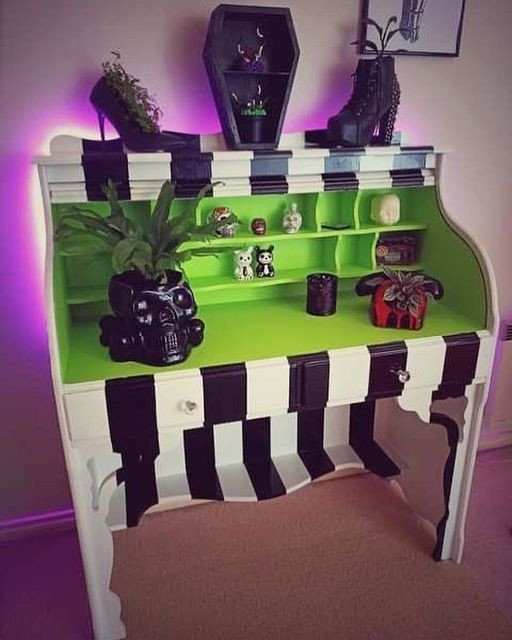 Ein hölzerner Schreibtisch, der in Schwarz, Weiß und Acid Green neu gestrichen und als Hommage an die Ästhetik des Films Beetlejuice dekoriert wurde