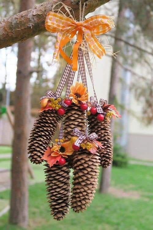 A hanging decoration with pine cones, orange bows and autumn leaves