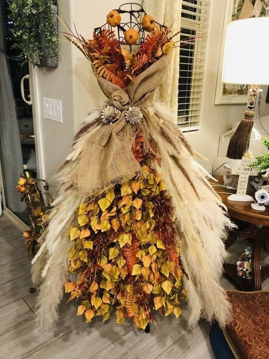 An old mannequin dressed up in an autumn theme using burlap, fall leaves and pumpkins