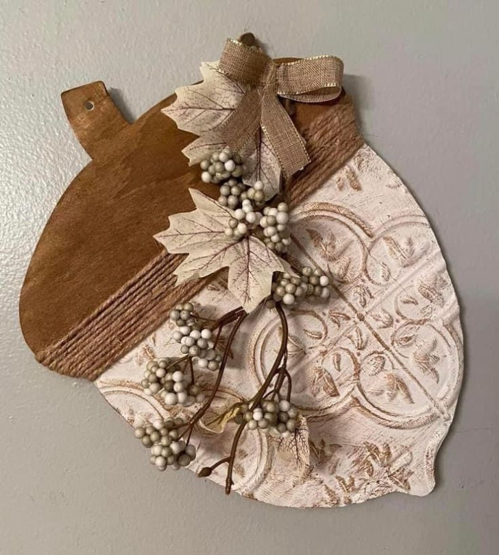 A wooden acorn decorated with twine, burlap, leaves and a branch of white berries