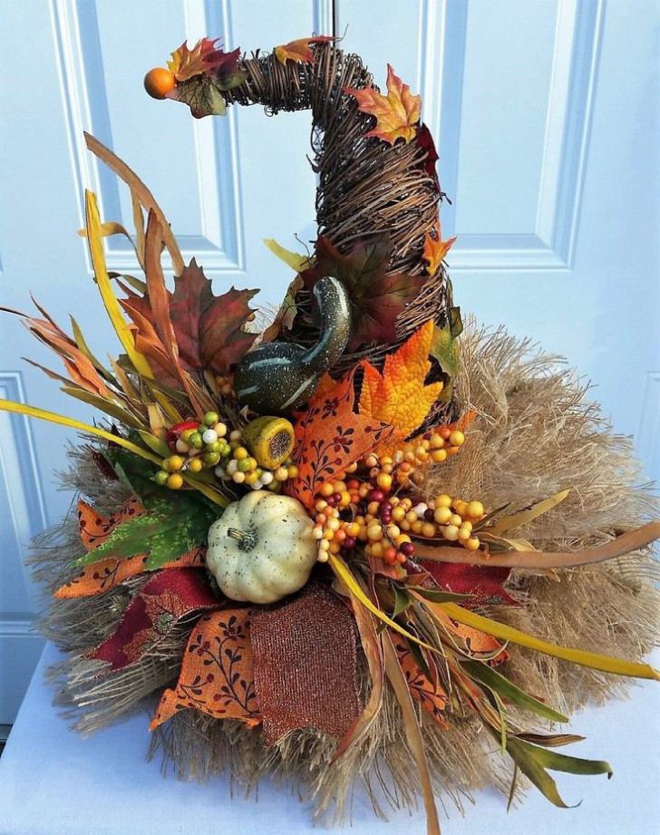 A witch's hat made with thin branches, burlap, leaves and small pumpkins