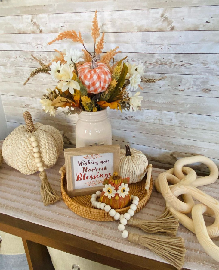 An entryway decoration in neutral tones made with rope pumpkins and dried flowers