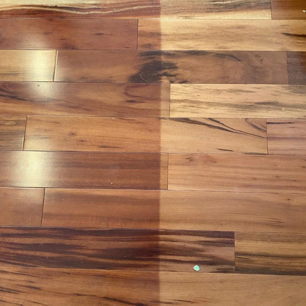 A wooden floor with a clear distinction in the colors between the area protected by a carpet and the area exposed to the sun