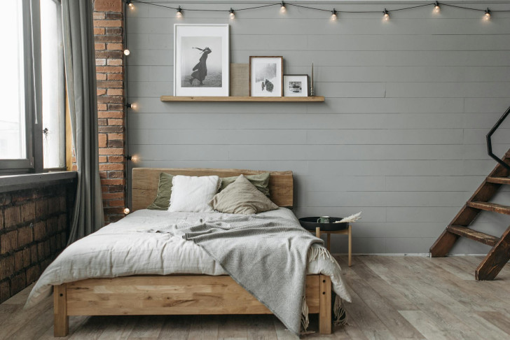 A shelf with paintings replaces the headboard of a bed