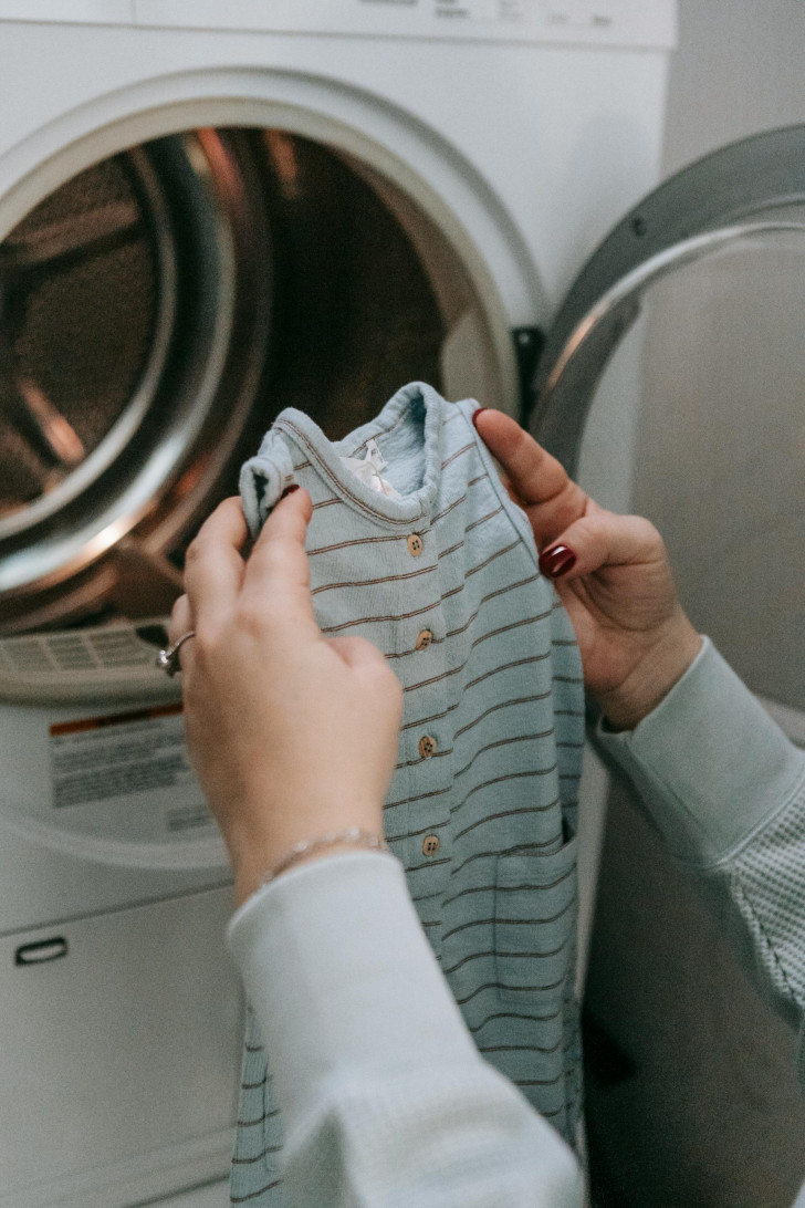 A baby's onesie being put into a washing machine