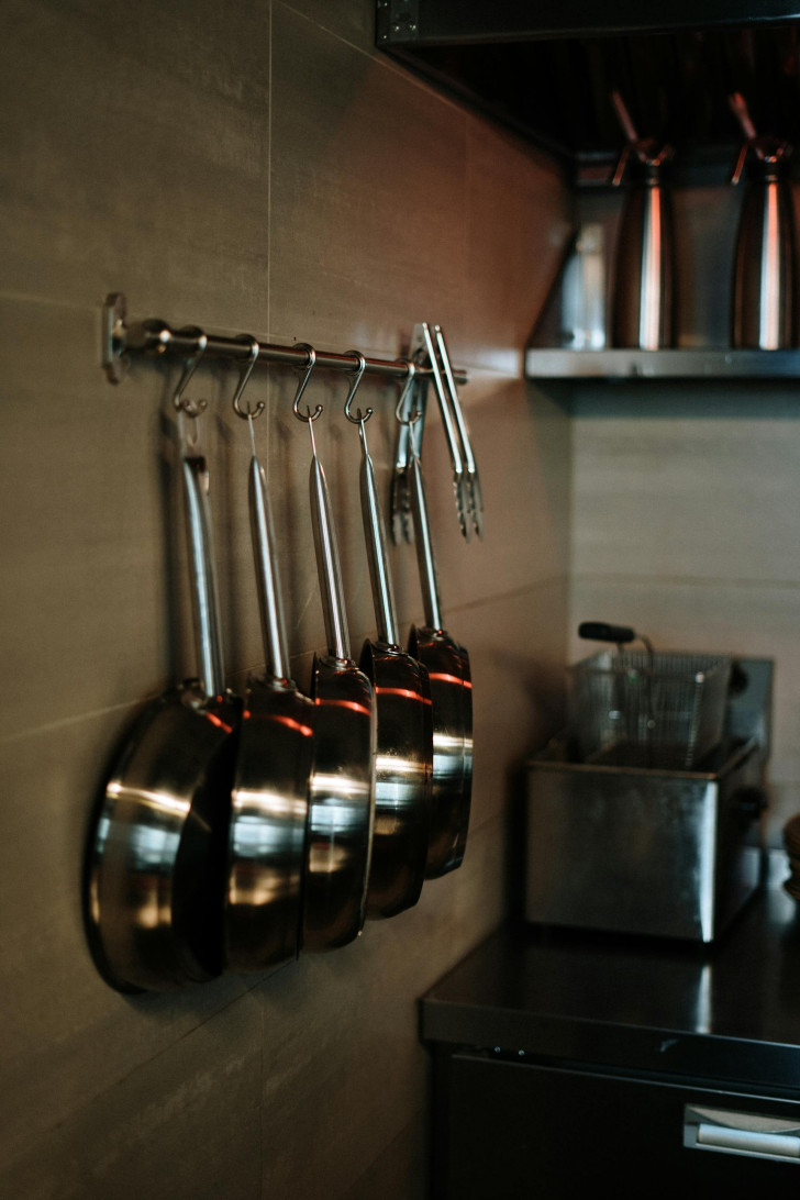 Stainless steel pans hanging on a rack in a kitchen