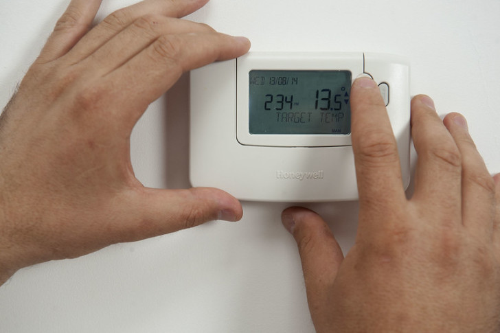 Un homme règle la température d'un thermostat