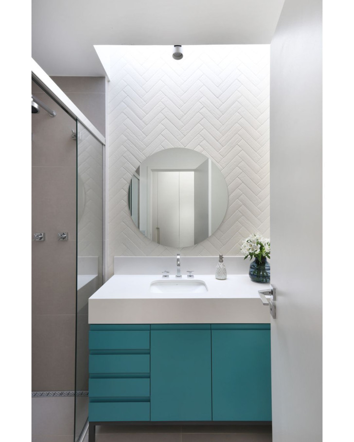 A small, all-white bathroom with an accented cabinet in lacquered turquoise