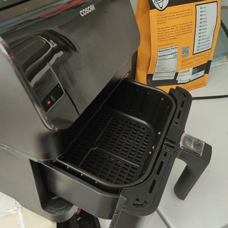 side view of an air fryer with open cooking drawer