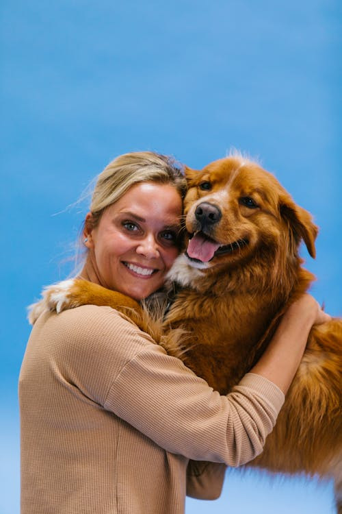 Una donna bionda abbraccia sorridendo un cane contento