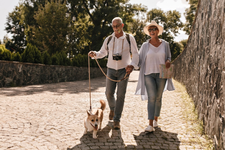 una coppia di persone di mezza età che passeggia con un cane a guinzaglio