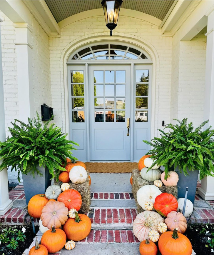 decorative pumpkins of various types placed on the steps of an entryway