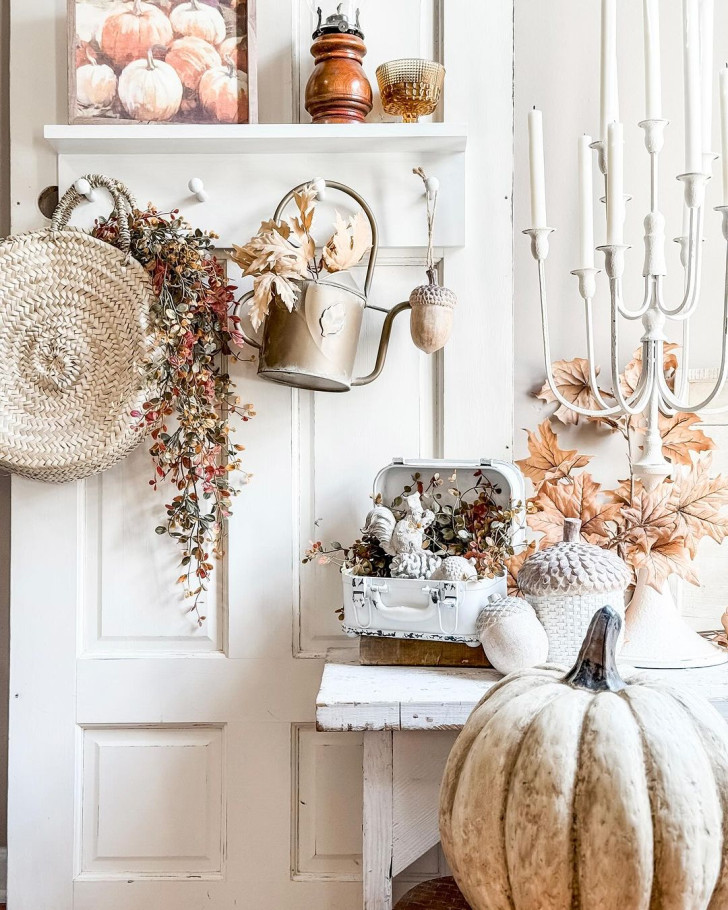 Decorative arrangement of pumpkins and fall leaves at the threshold of a house