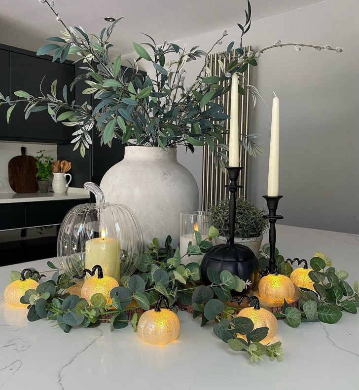 composition of leaves, glass candle holders and pumpkin-shaped lights