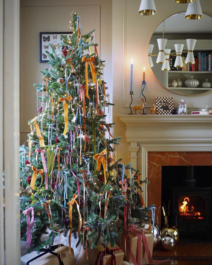 a Christmas tree decorated with colorful velvet bows on the tips of its branches