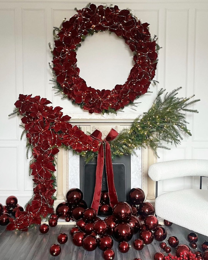 a fireplace decorated with a red Christmas garland and a wreath