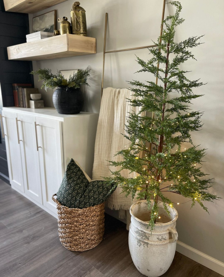 A living room with a Christmas tree placed in a white, terracotta pot