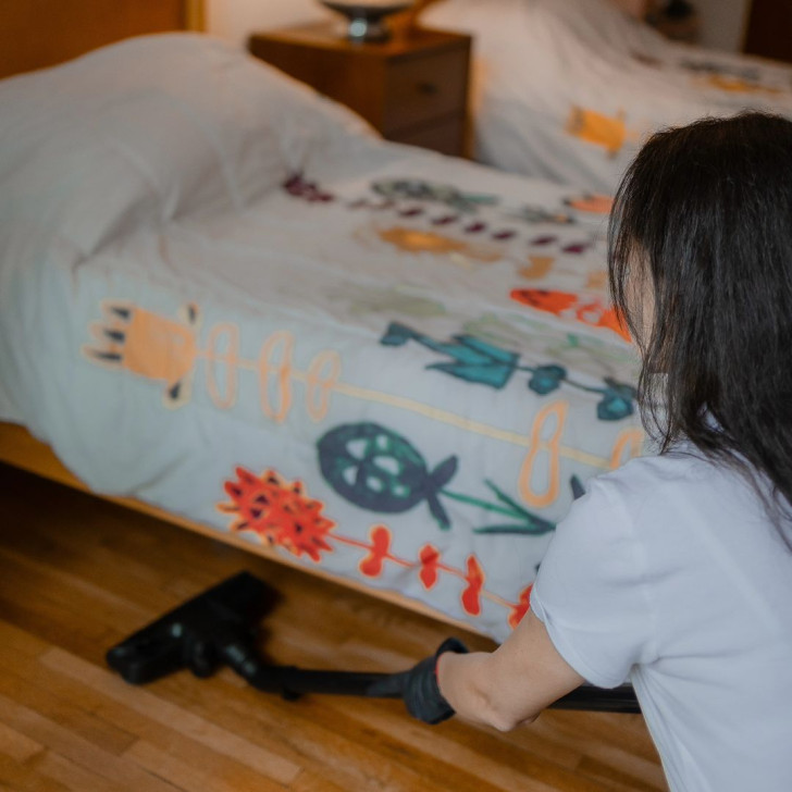 A woman vacuuming the floor of a children's bedroom