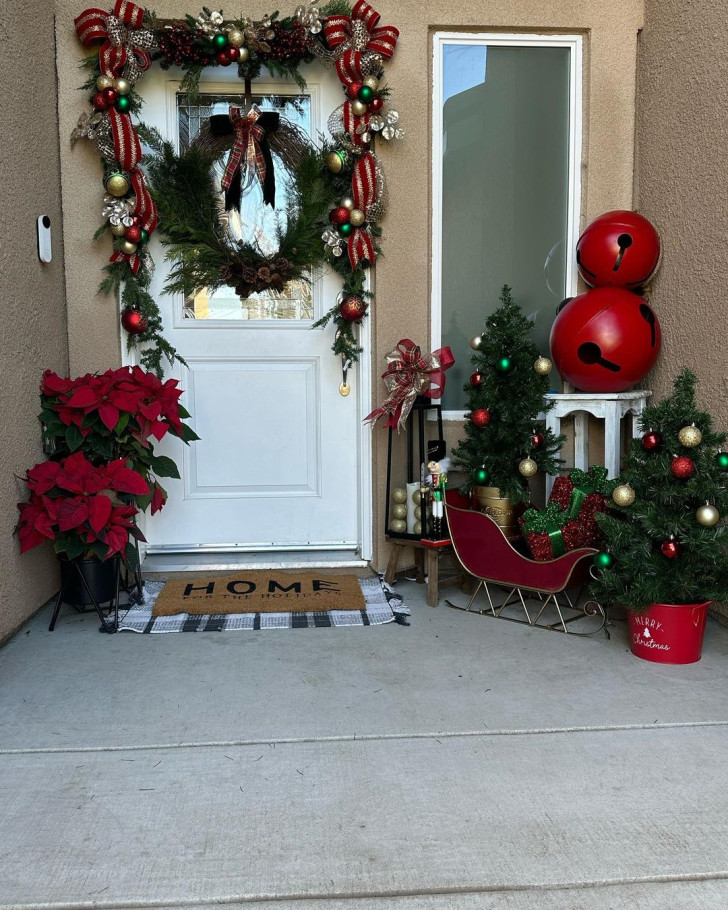 Étoiles de Noël, grandes boules rouges, petite luge et sapin décoré pour l’entrée