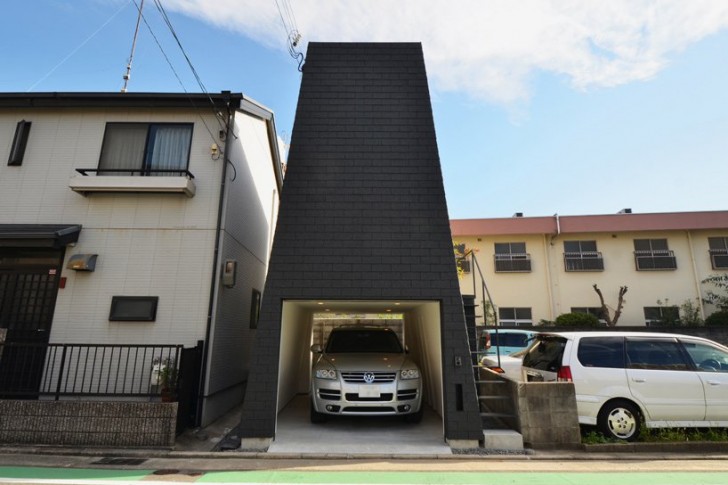 Un grande garage al piano terra, ed uno spazio tutto rivestito in legno al primo. La casa si trova in un quartiere residenziale in Giappone.