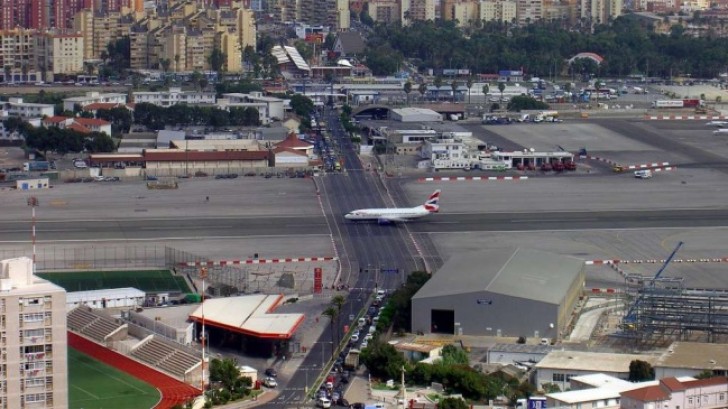 18. la piste de l'Aéroport International de Gibraltar, traversant une route parcourue par des automobiles