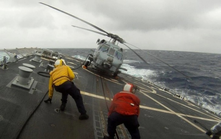 # 1. Opérateurs qui pilotent l'atterrissage d'un hélicoptère sur un navire en pleine tempête