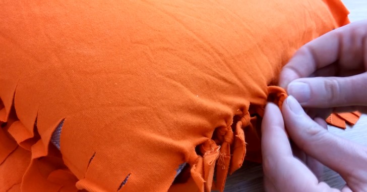 Placez le coussin entre les deux couches de tissu, et nouez une par une les franges.